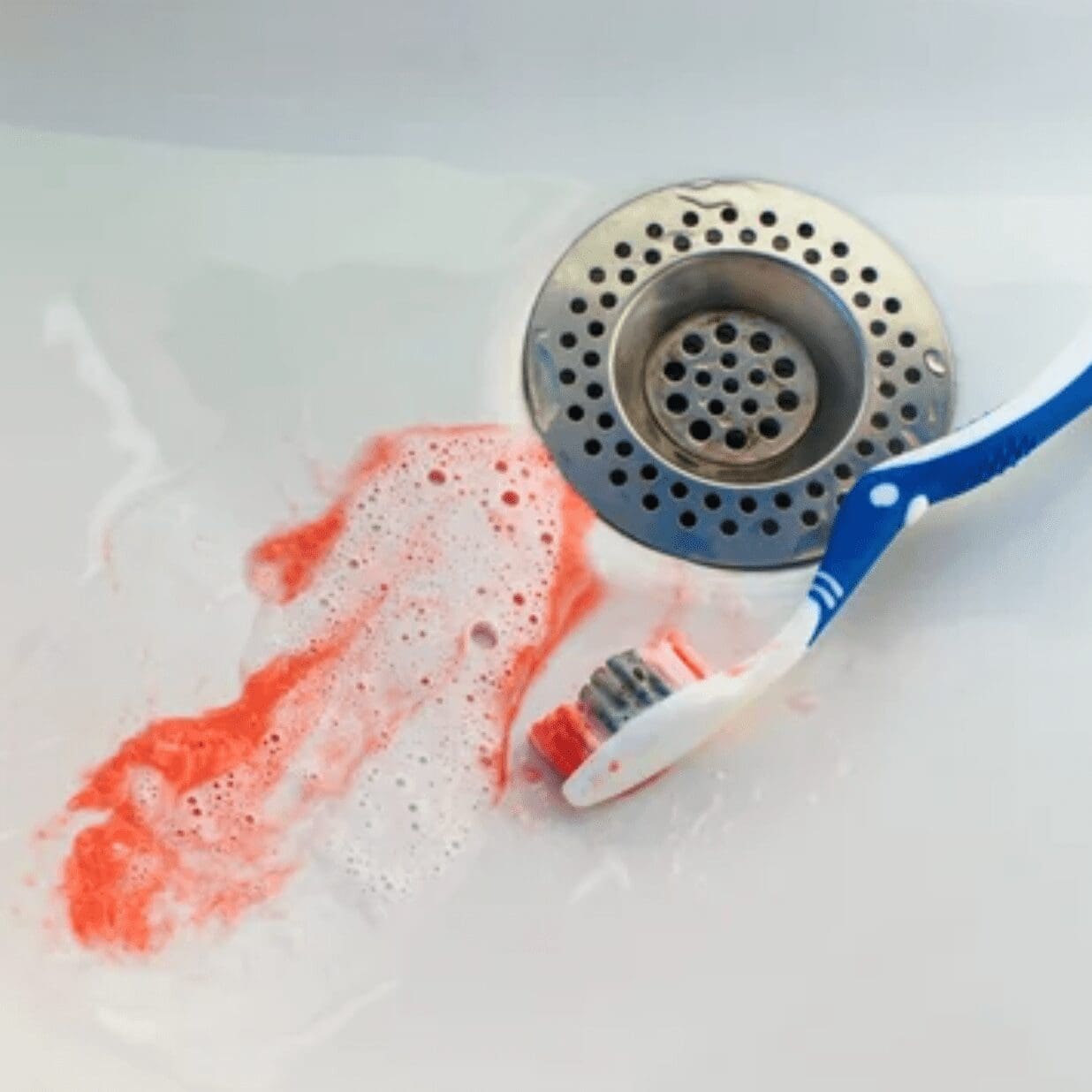 toothbrush in sink with toothpaste pink from blood bleeding gums dentist in Charleston South Carolina