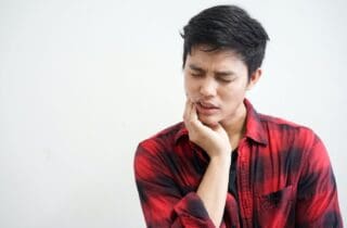 man using hand massage cheek cause from jaw pain tmj dentist in Charleston South Carolina